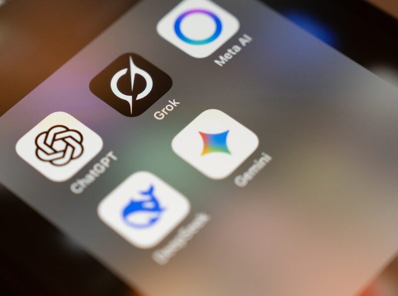 Smartphone screen displays ai app icons: chatgpt, grok, meta ai, gemini.